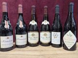 six bottles of wine are lined up on a wooden table