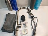 a picture of a sink with a hose, water bottle, and other items
