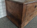 a wooden chest sitting on the floor in front of a yellow wall