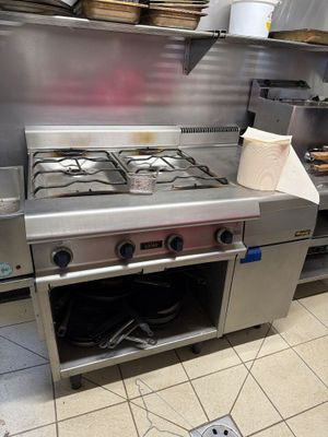 a stove in the middle of a kitchen with a bunch of dishes on the counter