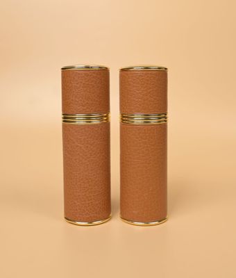 une paire de vases cylindriques en cuir marron sur fond beige