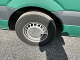 a green bus that has a flat tire on it