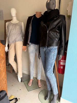 trois mannequins dans une pièce où sont exposés des vêtements