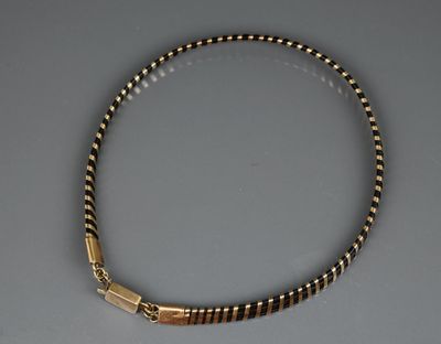 un gros plan d'un collier posé sur une table, sur fond gris
