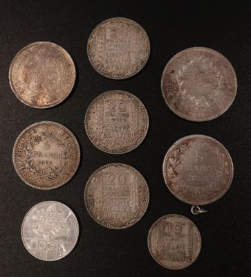 six different types of silver coins on a black surface