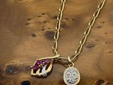 a close up of a necklace on a wooden surface with a coin
