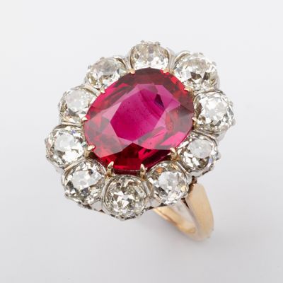 a close up of a pink and white diamond ring on a white surface