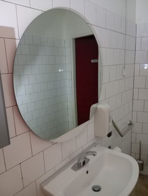 a bathroom with a sink, mirror, and toilet paper dispenser