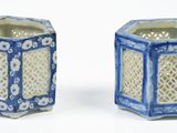 une paire de vases hexagonaux bleus et blancs posés sur une surface blanche