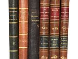 plusieurs vieux livres sont alignés sur une surface blanche