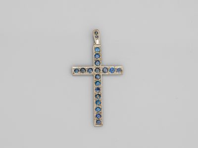 un pendentif en forme de croix orné de cristaux bleus sur fond blanc