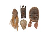 three wooden masks are sitting on a white surface