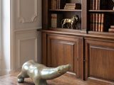 a statue of a bear sitting on a table in front of a bookshelf