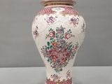 un vase blanc avec des fleurs roses sur une table
