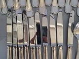 a lot of silver spoons and knives on the table