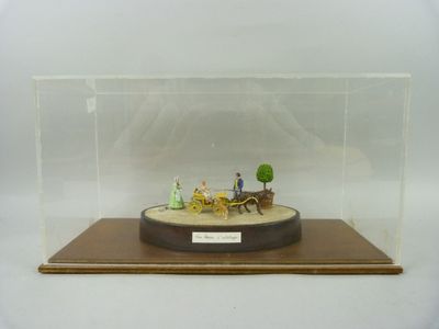 une maquette d'une calèche tirée par des chevaux, exposée dans une vitrine