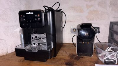 two coffee machines sitting on a table next to each other