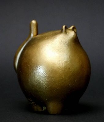 un vase doré orné d'un chat sur un fond noir
