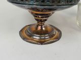 a blue glass bowl with a silver base on a white table