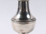 an antique silver salt shaker on a stand on a white background