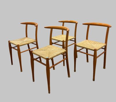four wooden chairs with wicker seats on a gray background