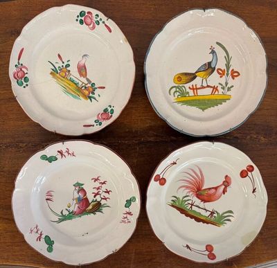 four plates with different designs on them sitting on a wooden table