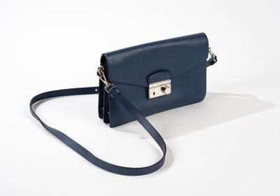 le petit sac à main bleu est posé sur une surface blanche
