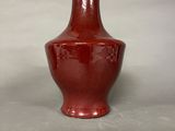 a red vase sitting on a table with a white background