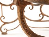 wrought iron bench with a plant on top of it on a white surface
