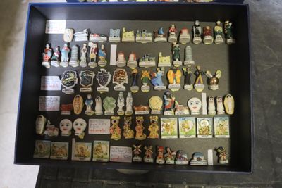 une vitrine posée par terre, remplie de pin's et d'aimants