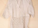white blouse with lace detail on a hanger on a wooden wall