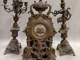 a clock that is sitting on a table next to three candles