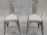 pair of silver metal chairs with wicker backrests