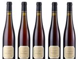 six bottles of wine sitting next to each other on a white surface