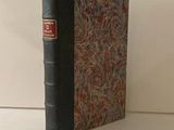 un livre noir à la couverture rouge posé sur une table blanche