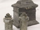 two small metal containers sitting next to each other on a white surface