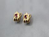 a pair of gold earrings with a ruby stone in the middle