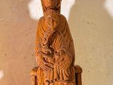 a wooden statue of a woman sitting on a bench
