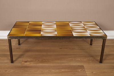 une table basse avec un plateau en carrelage posée sur un parquet