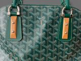 a close up of a green and brown handbag on a table