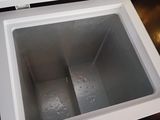 a small white freezer that is open on the floor