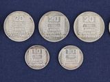 six different types of silver coins on a blue background