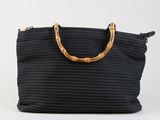 un sac noir tissé, muni de poignées en bambou et d'une poignée en bois