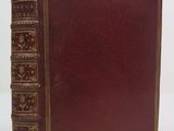 un vieux livre à la couverture rouge posé sur une surface blanche