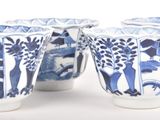 four blue and white cups with animals and trees on them