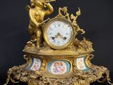 a gold clock with a cupid playing a flute