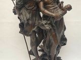 bronze statue of a couple holding a child on a wooden base