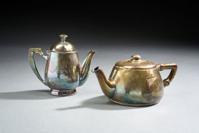 une paire de théières anciennes en argent posées sur une table devant un fond noir