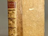 un vieux livre posé sur une table à côté d'un mur gris
