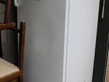 un réfrigérateur blanc posé à côté d'une chaise dans une pièce